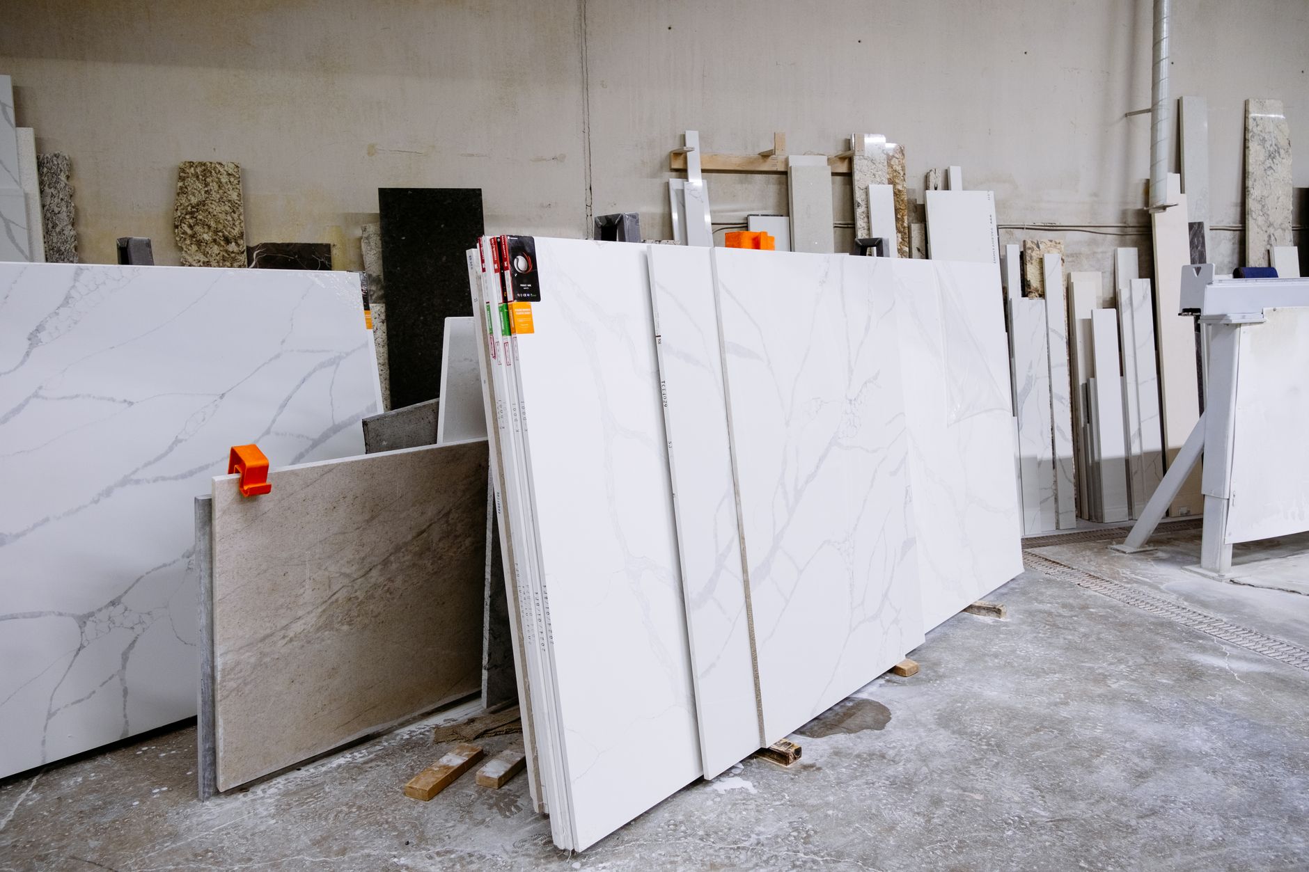 Veined white quartz slabs leaning on wood blocks in a fabrication shop